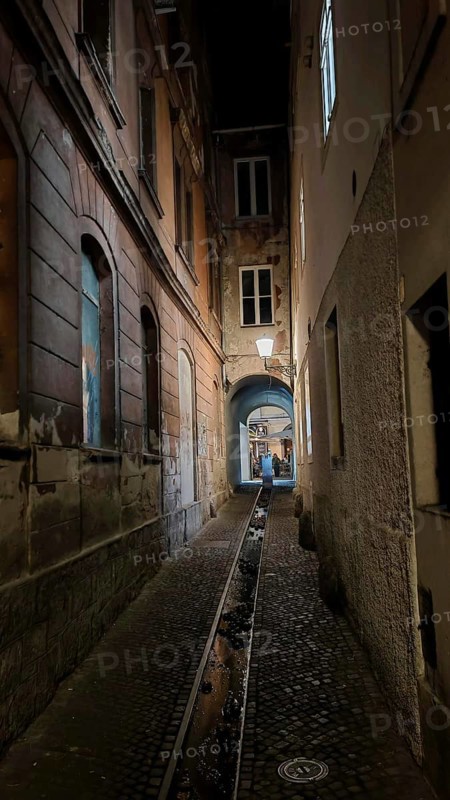 Dark, narrow alley at night with cobblestones and dim lantern light, urban atmosphere, Ljubljana, Slovenia
