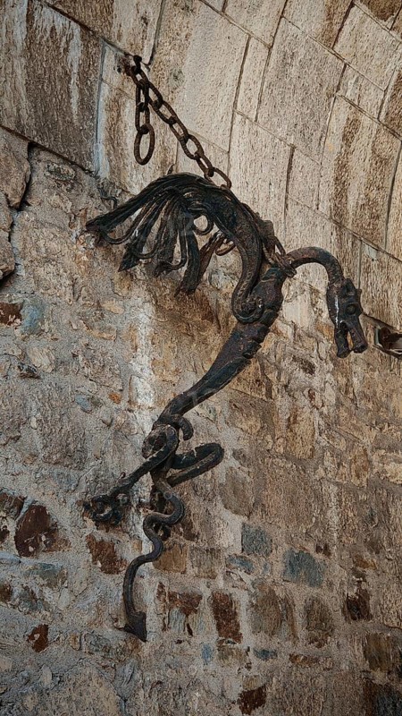 Ancient metal sculpture, Ljubljana dragon hanging on a stone wall surrounded by historic architecture, Ljubljana, Slovenia