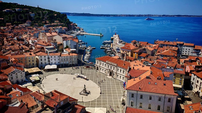 Aerial view of a coastal town with red roofs, a harbor and a main square on the blue sea, Piran, Slovenia