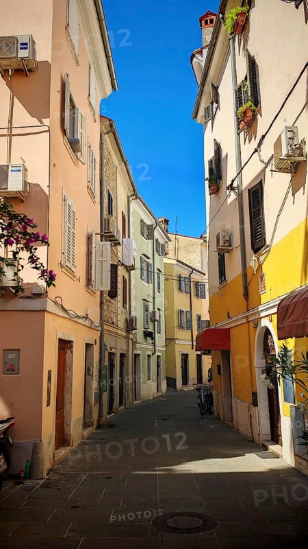 A narrow, colorful alley in a Mediterranean town in bright sunshine, Piran, Slovenia