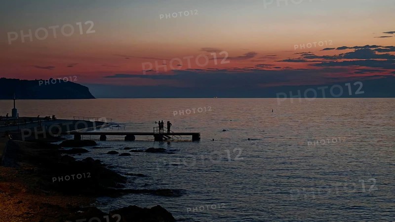 A peaceful sunset with silhouettes of people by the sea, Izola, Slovenia