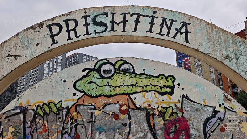 Graffiti of a cartoonish alligator under a large bow with the inscription Prishtina, Pristina, Kosovo