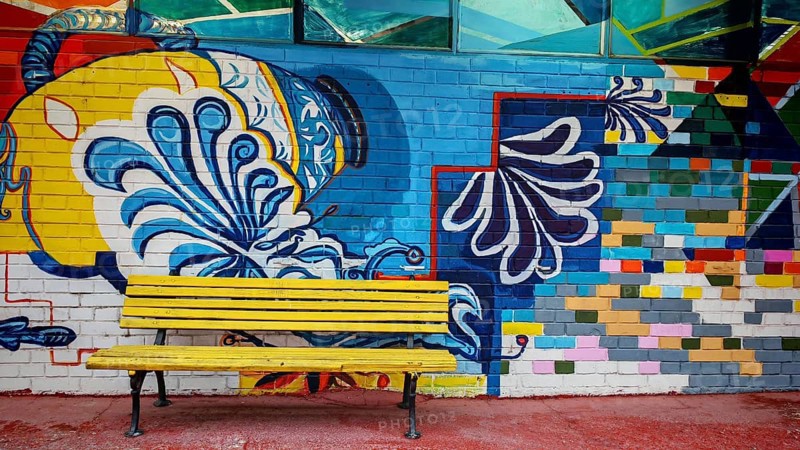 Colourful wall painting with geometric patterns and a yellow bench in the foreground, Skopje, North Macedonia