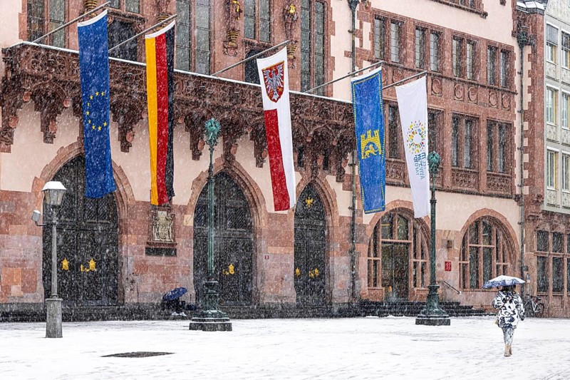 A passer-by walks across Frankfurt's Römerberg with an umbrella. Heavy snowfalls have caused another onset of winter in the Main metropolis, Osthafen, Frankfurt am Main, Hesse, Germany