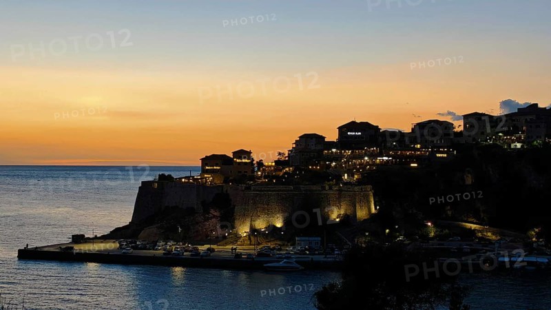 Dusk over an illuminated fortress on a coast with calm sea and warm sky, Ulcinj, Montenegro