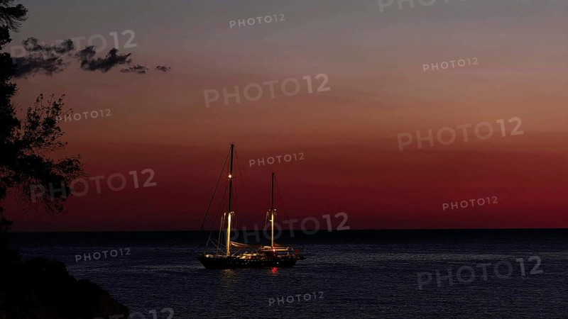 A sailboat at sunset on calm water surrounded by an atmospheric dusk, Ulcinj, Montenegro