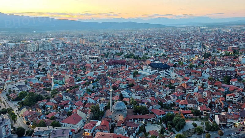 Panoramic photo of city at sunset with distinctive mosque roof and mountains, Prizren, Kosovo