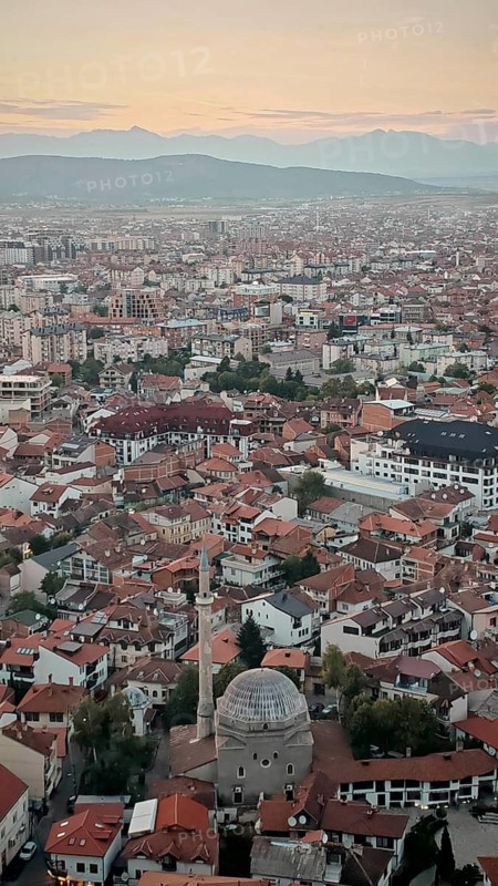 Wide view of a city at sunset with a distinctive mosque and red roofs, Prizren, Kosovo