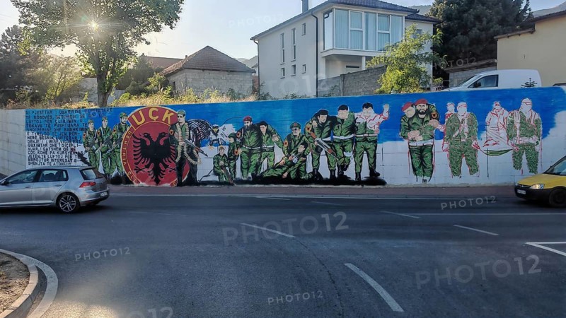 Wall painting of soldiers with KLA emblem on a street corner, Kosovo