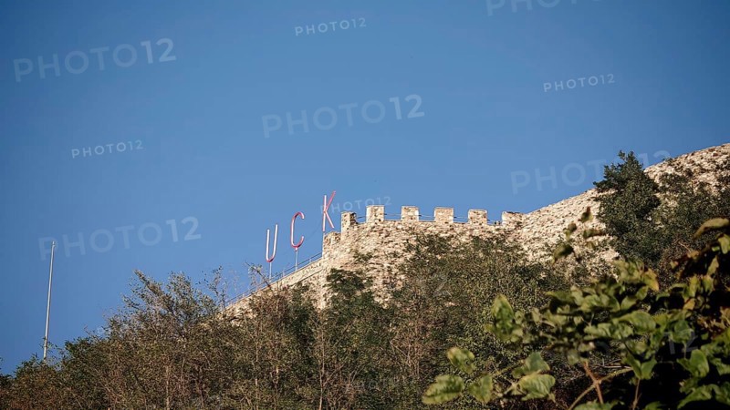 KLA lettering on an old castle on a hill with trees and blue sky, Prizren, Kosovo