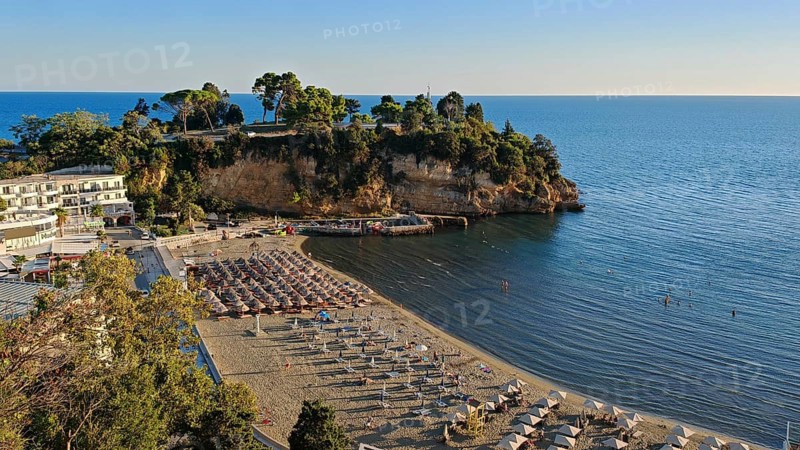 Sunny beach area with umbrellas and clear, blue sea on the coast, Montenegro