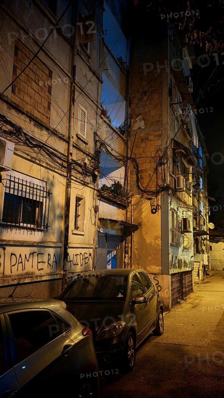 Night view of a city street with parked cars and worn buildings, Tirana, Albania