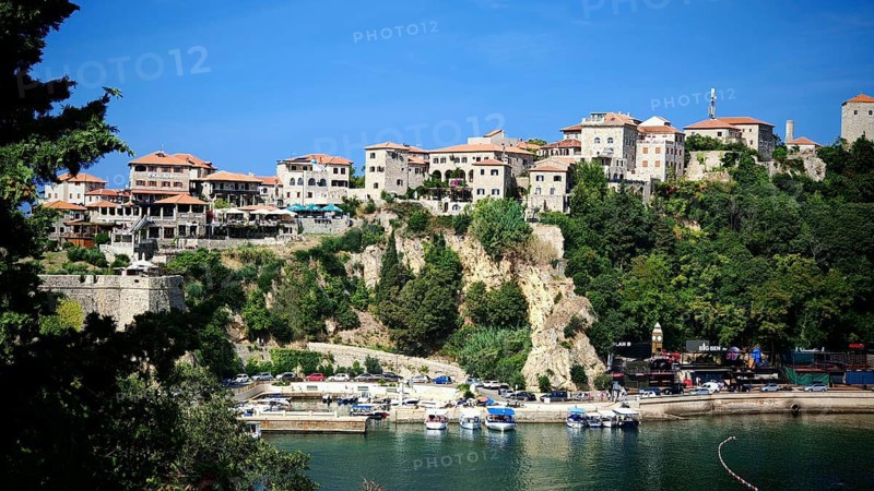 Medieval town on cliff with blue sky and harbor with boats, view of Ulcinj, Montenegro
