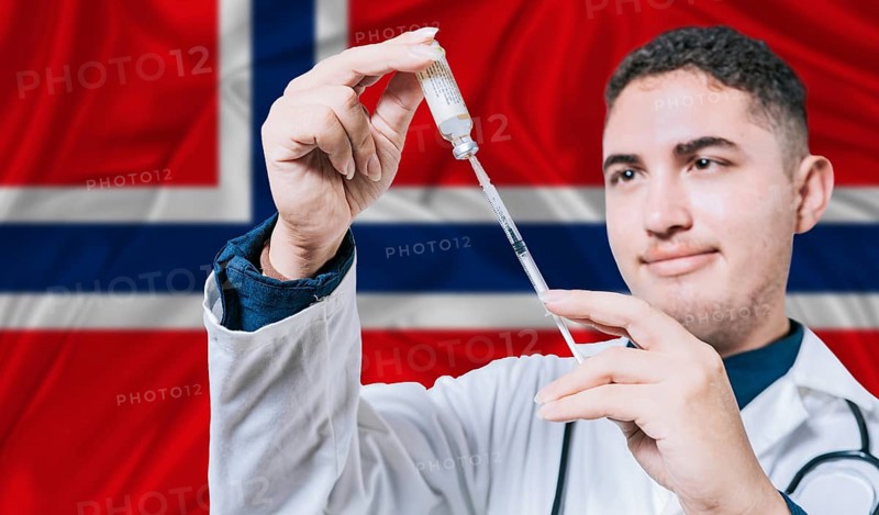 Doctor holding syringe on Norway flag background. Medical professional holding syringe with Norwegian flag in the background
