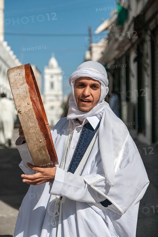 Tripoli, Libya, North Africa. A young man in traditional clothes in the historic quarter with 'tambur' during Milhud