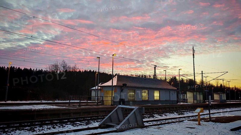 A small train station at dawn under a colorful sky with snow-covered ground, Rennsteig, Frankenwald nature park Park