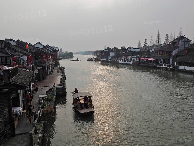 A leisurely evening view across the canal with traditional buildings and boat traffic, Zhujiajiao Ancient Town, Shanghai, China