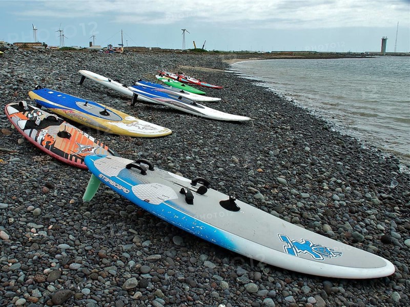 Pebble beach with colorful surfboards at sea under cloudy sky, Pozo Izquierdo, Gran Canaria, Canary Islands, Canary Islands, Spain
