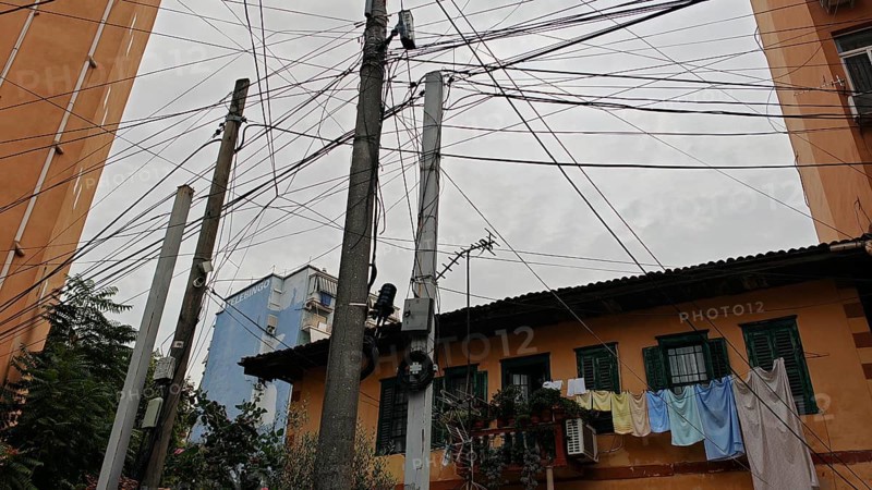 Power poles with a tangle of wires, next to buildings and clotheslines, create an urban image, Tirana, Albania