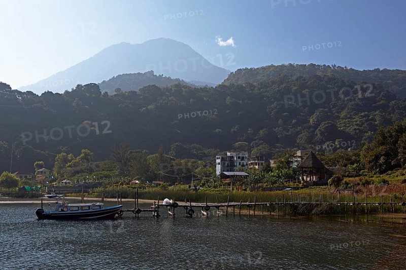 Colourful boats in the port of San Juan la Laguna, behind the Dan Pedro volcano in the haze, Atitlán, Sololá Department, Guatemala