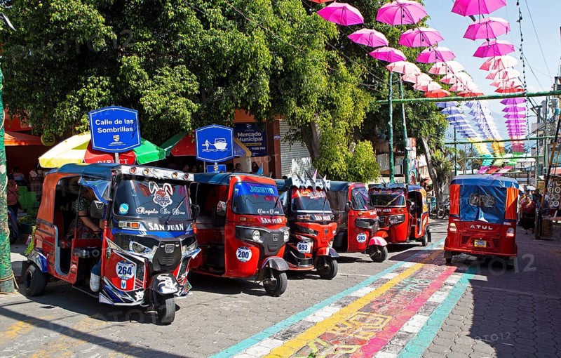 Red tuk tuks or tricycle taxis in an alley in San Juan la Laguna, Atitlán, Sololá Department, Guatemala
