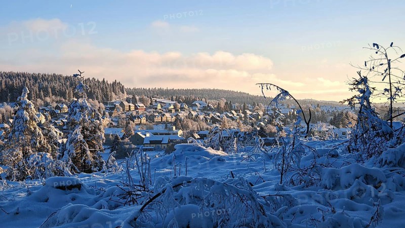 Winter village in snowy landscape with hills and forests in the evening light, Rennsteig, Thuringian Forest nature park Park