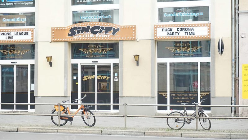 Club façade with posters and two bicycles in the foreground and sign Fuckcorona during corona, Berlin