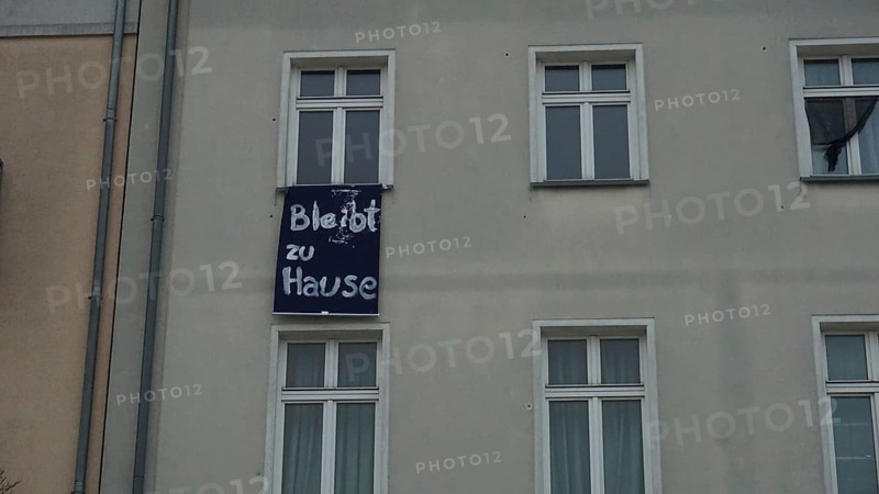 House façade with lettering stays at home during corona on a banner between windows, Berlin