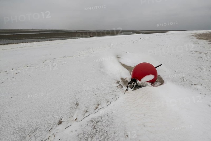 Red buoy on snowy beach, Langeoog, Lower Saxony, Germany
