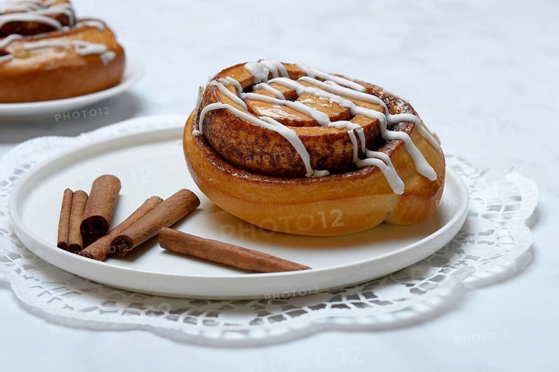 Cinnamon roll on plate and cinnamon sticks