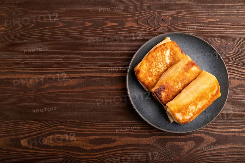 Fried crispy pancakes with meat and cheese on brown wooden background. top view, flat lay, copy space