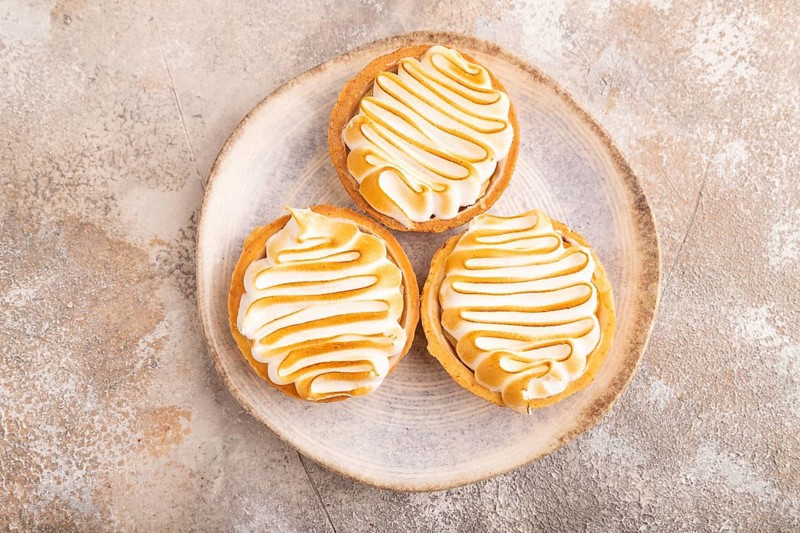 French lemon tart with meringue on brown concrete background, top view, flat lay, close up