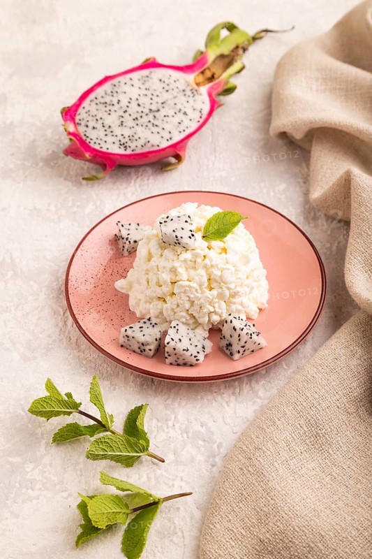 White ?ottage cheese, Curd, with Pithaya on gray concrete background and linen textile, side view, close up