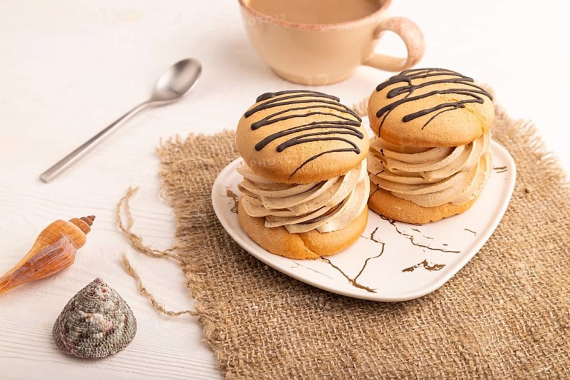 Caramel Cream Cakes on white wooden background and linen textile, cup of coffee, side view, close up