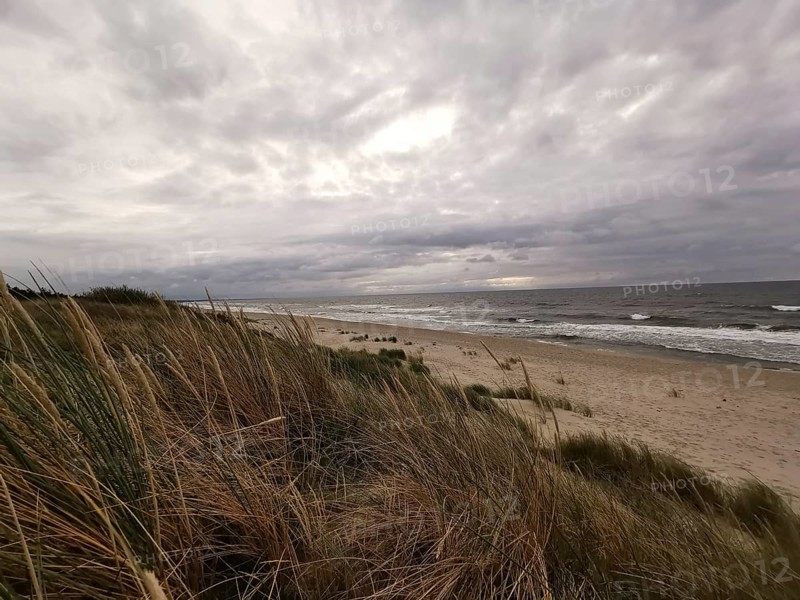 Sandy dunes on the beach with cloudy sky and rough sea in the background, Baltic Sea, fresh spit, Pomerania, Poland