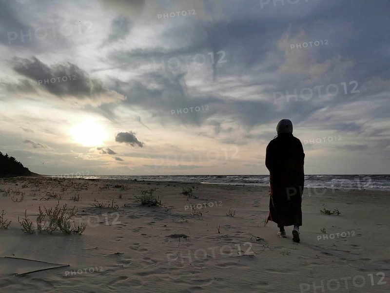 A person standing on the beach looking at the sea at sunset, atmospheric scene, Baltic Sea, fresh spit, Pomerania, Poland