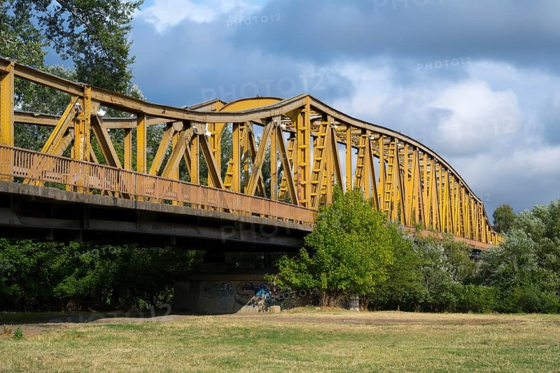 Yellow metal bridge over a meadow with trees, a river and cloudy sky in the background, bridge over the Morava river, Cuprija, Cuprija, Pomoravlje district, Serbia Europe
