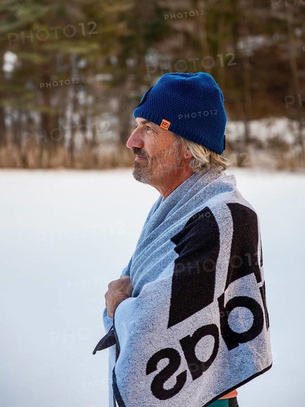 Man with cap, 55, standing on the ice wrapped in a towel after ice bathing, Thumsee, Bad Reichenhall, Berchtesgadener Land, Upper Bavaria, Bavaria, Germany
