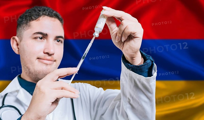 Doctor holding syringe on Armenia flag background. Medical professional holding syringe with Armenian flag in the background