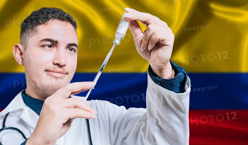 Doctor holding syringe on Colombia flag background. Medical professional holding syringe with Colombian flag in the background