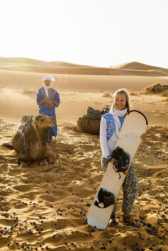 Young woman with snowboard in the sand dunes, near Merzouga, Meknès-Tafilalet region, Erg Chebbi, northern Sahara, Morocco