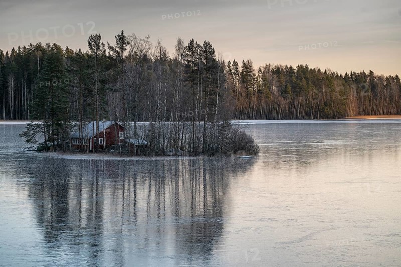 Small island with a red house, frozen lake, edge of forest, winter, Hartola, Finland