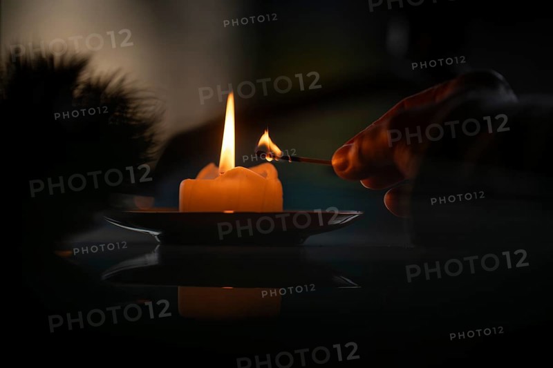 Hand still holding a burning match after a yellow candle is lit, Christmas atmosphere, Finland