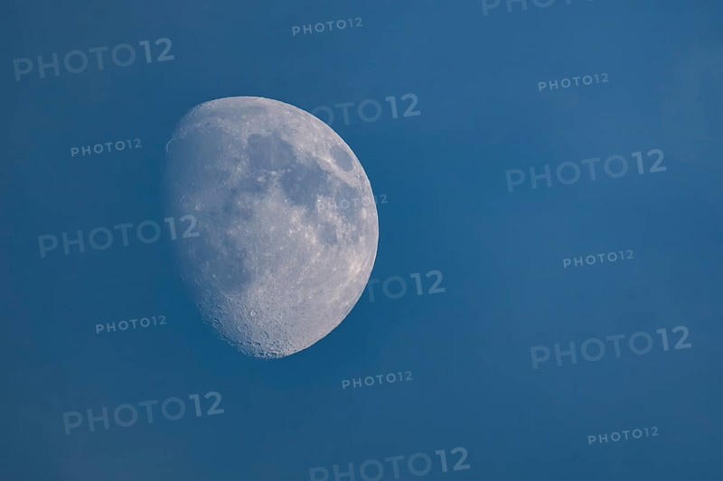 Detailed image of the waxing moon with visible craters and spots during the day, dividing line between the day and night sides of the moon visible, Finland