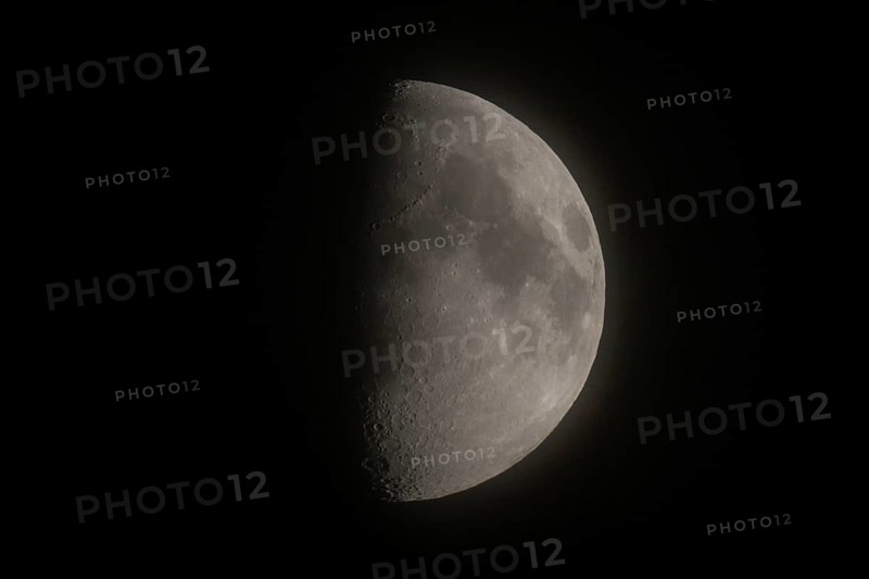 Detailed image of the waxing moon with visible craters and spots at night, dividing line between the day and night sides of the moon