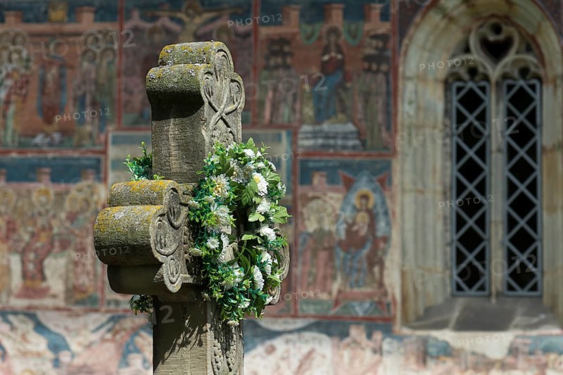 Artificial flower wreath on a stone cross in front of the Romanian Orthodox Women's Monastery, 1530, Gura Humorului, Romania