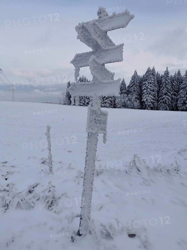 Snowy signpost in a winter landscape with forest in the background, Rennsteig, Frankenwald