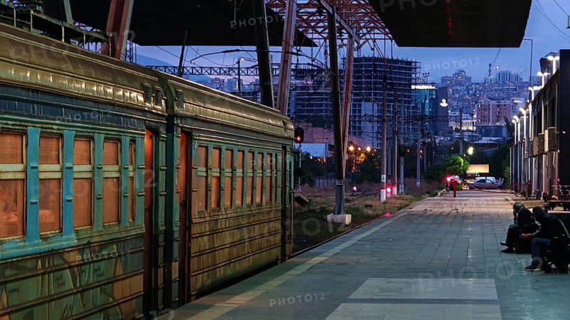 Illuminated train station with old train and city scenery at dusk, Yerevan, Armenia