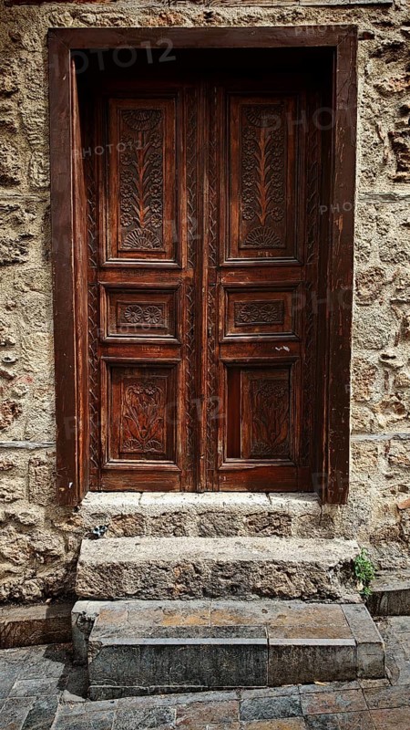 Decorated antique wooden door set into a rough stone wall, Antalya Turkey