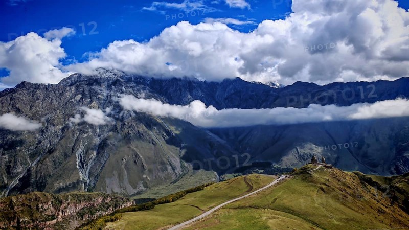 Impressive mountain landscape with clouds and blue sky, Gergeti Monastery, Georgia